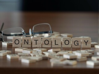 Wall Mural - ontology word or concept represented by wooden letter tiles on a wooden table with glasses and a book