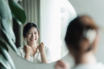 A young Asian woman talks to herself through a mirror to build her self-confidence and empower herself.