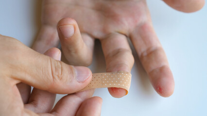 male applying band aid patch to injured sore fingers. man putting medical adhesive bandage tape stic