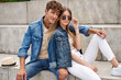 Leinwandbild Motiv Photo of attractive couple wear denim clothes sitting outdoor and looking at camera
