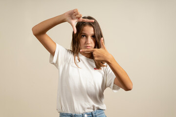 Wall Mural - Teenage latin girl wearing casual white t-shirt smiling making frame with hands and fingers with happy face. creativity and photography concept