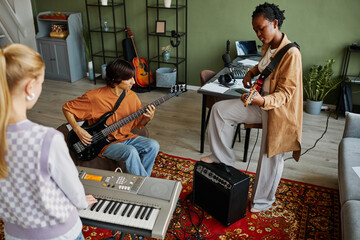 Wall Mural - Dynamic shot of young music band playing instruments together while practicing in cozy studio