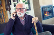 © Solid photos - Serious senior man with walking cane talking n the phone in winter