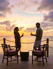 couple drinking cocktails on the beach with palm trees and watching the sunset at the tropical beach of Saint Lucia or St Lucia Caribbean. men and women on vacation on tropical island with palm trees