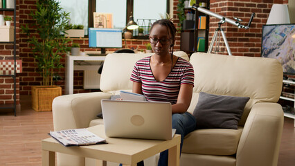 Poster - African american woman doing remote work on laptop at home, using online connection to learn about startup business. Working remotely on computer, doing freelance job and research.