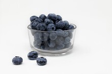 Closeup shot of fresh organic blueberries in a glass bowl against the white background