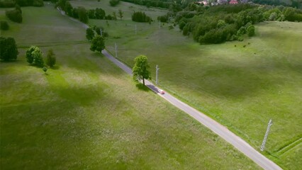 Sticker - Drone shot of a road between large green spaces with trees