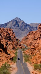 Poster - Asphalt road surrounded by rock formations leading to a huge mountain in sunny weather