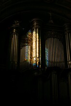 Vertical Shot Of Beautiful Organ Pipes With A Rainbow Reflection On Them In Dark