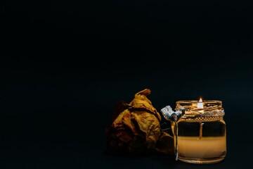 Sticker - Decorative candle burning in the glass and a dry rose isolated on the black background