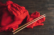 Knitted red hat, scarf, knitted mittens and wooden knitting needles on wooden background. Hobby craft. Concept of knitting, needlework.