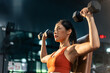 © Kawee - Asian sportswoman slowly lift up weight machine or barbell in stadium