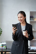 © amnaj - Beautiful Asian businesswoman is using her smartphone to chat with customers in a relaxed workplace with a smile and a good mood.