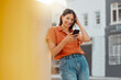 © K Abrahams/peopleimages.com - Woman texting, browsing and scrolling on phone while chatting on social media, waiting for taxi and commuting in an urban city. Happy, trendy and smiling female tourist reading online notification