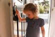 © Austockphoto - close up shot of a smiling girl wearing blue dress holding the door handle while looking down