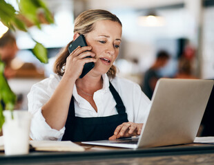 Canvas Print - Coffee shop owner on a phone call while working online on her laptop inside a local cafe store. Contact us, learn about us and talk to our baristas, managers and small startup business entrepreneurs