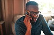 © Chanelle Malambo/peopleimages.com - Young student talking on a phone call to a friend, colleague or family member. Black male university or college learner studying design, marketing or architecture sitting and chatting at home