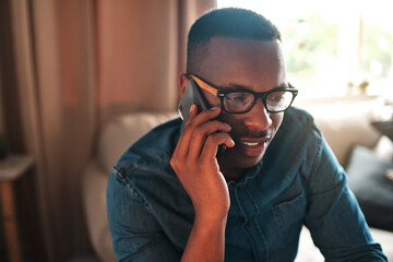 Aufkleber - Young student talking on a phone call to a friend, colleague or family member. Black male university or college learner studying design, marketing or architecture sitting and chatting at home