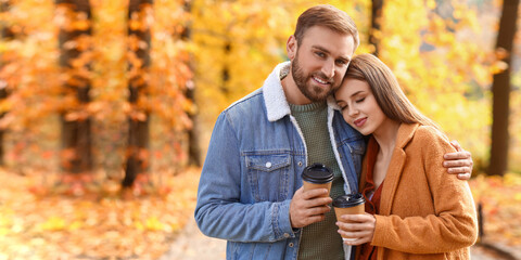 Poster - Happy young couple with cups of coffee in autumn park