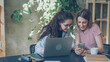 © silverkblack - Young enterpreneurs are talking and looking at smart phone while sitting at desk in modern office.