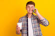 © Tetiana - Photo of young cheerful man talk cellphone enjoy morning americano isolated over yellow color background