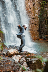 Wall Mural - young pretty woman hiking enjoying view of waterfall