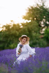 Wall Mural - Romantic young woman in a white dress and straw hat in a lavender field on the sunset	