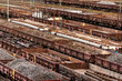 Offene Güterwaggons teilweise mit Rungen und beladen mit Kohle, Schotter, Gleisen und Altmetall warten auf einem Rangierbahnhof auf den Weitertransport