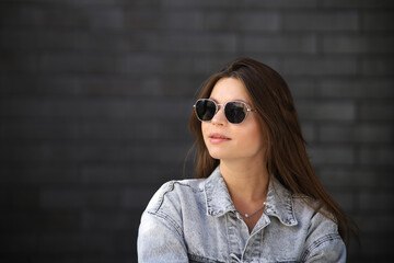 Wall Mural - Close up portrait of a fashionable young woman in modern sunglasses over brick wall background. Street style. Beauty, fashion concept. Optics, eyewear.