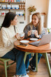 © Drobot Dean - White women smiling and talking while drinking tea in cafe