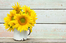 A Bouquet Of Sunflowers In A Metal Mug On A Wooden Bar