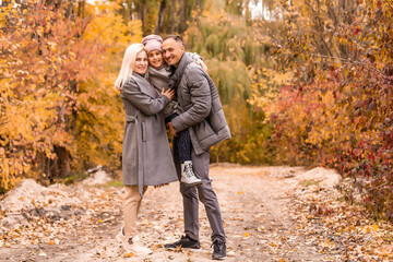 Wall Mural - A Family of four enjoying golden leaves in autumn park