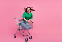 Full Length Portrait Of Cheerful Overjoyed Girl Sitting Inside Supermarket Trolley Isolated On Pink Color Background
