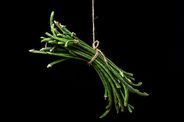 Poster - Green string beans tied in a bunch hanging on a black background. Delicious and healthy vegetable