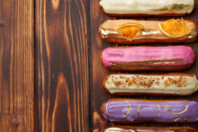 Assortment Of Sweet And Colorful Eclairs On Wooden Background