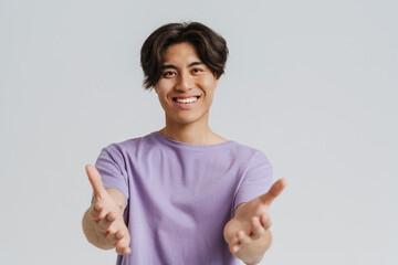 Wall Mural - Young asian smiling boy in violet t-shirt spreading palms