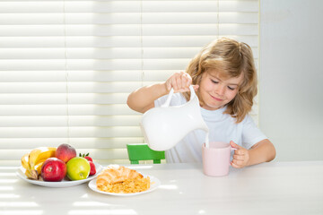 Wall Mural - School chil pouring whole cows milk for breakfast. Child in the kitchen at the table eating vegetable and fruits during the dinner lunch. Healthy food, vegetable dish.