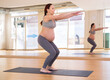 Pregnant woman is engaged in yoga. Exercise in a bent position with arms extended forward