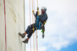 © chitsanupong - Male worker inspection wearing safety first harness rope safety line working at a high place on tank roof spherical gas  blue sky