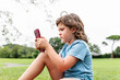 © ADDICTIVE STOCK - Girl using smartphone on park lawn