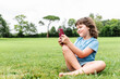 © ADDICTIVE STOCK - Cheerful girl using smartphone on park lawn