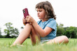 © ADDICTIVE STOCK - Girl using smartphone on park lawn