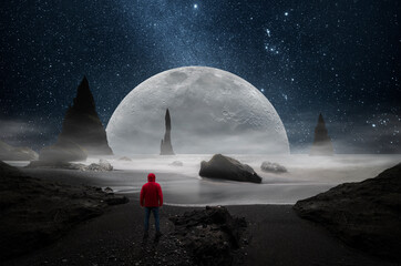 Wall Mural - man observing a huge moon from a beach