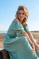 The girl is sitting on the sandy beach.