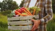 © Acronym - Farmer with a vegetable box in front of a sunset agricultural landscape. Man in a countryside field. Country life, food production, farming and country lifestyle.