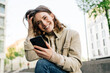 © contrastwerkstatt - Young woman with cell phone looks at camera laughing