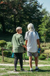 © LIGHTFIELD STUDIOS - happy retired woman in sportswear looking at husband with sport bottle and holding hands in park.
