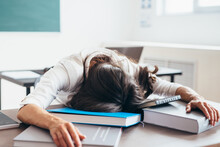 Tired Female Student Sleeping On Desk Face And Hands On Books