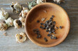 Collecting hollyhock flower seeds from dried seed pods. Top view of hollyhock seeds in wooden bowl
