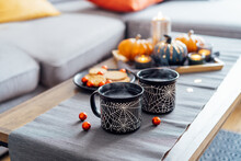 Cozy Halloween Plans At Home. Hot Tea Drink In Black Mugs With Spider Net Pattern, Cookies And And Sweets On The Plate, Pumpkin Decor On The Coffee Table. Festive Autumn, Fall Mood Home Decor